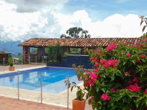 una piscina frente a una casa con flores rosas en Hotel Campestre El Santuario, en Barichara