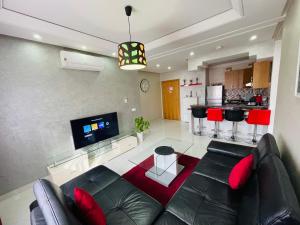a living room with a black leather couch and a kitchen at Modern Apartment in the heart of Tangier in Tangier