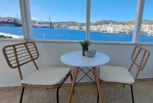 two chairs and a table in a room with a window at Casa di Syrii in Ermoupoli