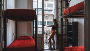 a woman looking out the window of a room with bunk beds at IDEAL SOCIAL Hostel in Buenos Aires