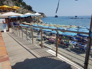 a beach with chairs and umbrellas and people on the beach at Monterosso Servano's Villas in Monterosso al Mare