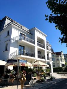 Biały budynek ze stołami i parasolami przed nim w obiekcie Luxury Apartments in Residence Maritime w mieście Międzyzdroje