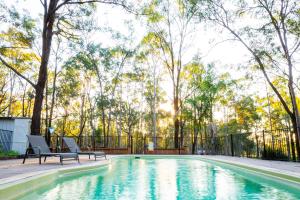 a swimming pool with two chairs and trees at Wild Woods at Pokolbin in Pokolbin