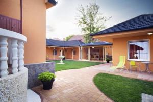 a house with a patio and a yard with chairs at Sunshine SH apartmanház in Zamárdi