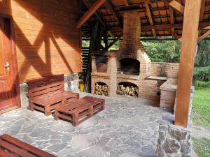 a patio with a brick fireplace and a bench at Casa de Vacanta Dintre Brazi in Topliţa