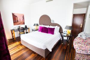 a bedroom with a large white bed with pink pillows at The Ambassador in Geneva