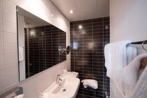 a black tiled bathroom with a sink and a mirror at The Ambassador in Geneva