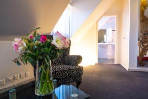 a vase of flowers sitting on a table next to a chair at The Ambassador in Geneva