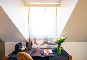 a desk with a vase of flowers and a window at The Ambassador in Geneva