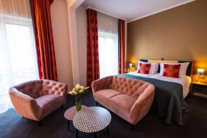 ジュネーヴにあるジ アンバサダーのベッド1台と椅子2脚が備わるホテルルームです。