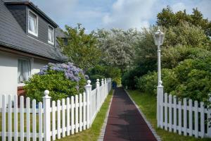 a white picket fence and a street light next to a house at Hotel Wiesbaden in Wenningstedt