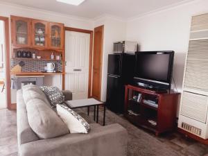 a living room with a couch and a flat screen tv at Central to CBD CoSheirm Apartments On Merri in Warrnambool