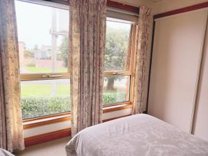 a bedroom with a bed and a large window at Central to CBD CoSheirm Apartments On Merri in Warrnambool