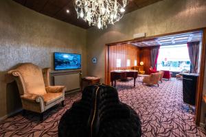 a living room with a tv and a couch and chairs at The Ambassador in Geneva
