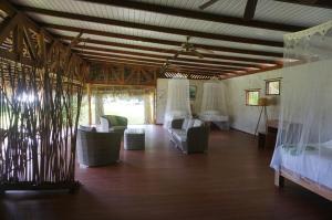 una stanza con sedie, un letto e un tavolo di Vanira Lodge a Teahupoo