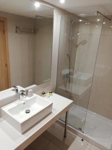 Un baño blanco con lavabo y ducha. en JOY Hotel Apts, en Ayia Napa