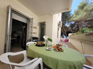 Rivabella的住宿－FRONTE PINETA MARE RIVABELLA，一张桌子,上面有绿色的桌布和白色的椅子