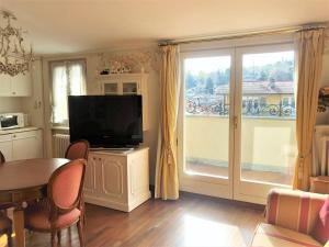 sala de estar con TV, mesa y ventana en Suite Romantic vista Lago, en Stresa