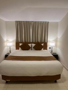 - une chambre avec un grand lit et deux lampes dans l'établissement اجنحة مجمع القوافل الفندقيه, à Tabuk