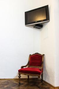 a red chair with a tv on a wall at Roth´s Apartment in Košice +32 photos