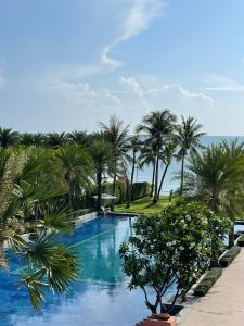 una piscina con palmeras en un resort en Baan Marakesh Hua Hin, en Hua Hin