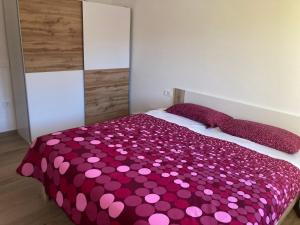 een slaapkamer met een groot bed met roze stippen bij First Vrtovin Apartment in Črniče