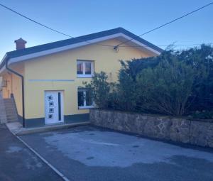 a small yellow house with a stone wall at First Vrtovin Apartment in Črniče