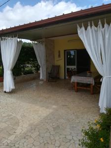 eine Terrasse mit weißen Vorhängen und einem Tisch in der Unterkunft VILLETTA SALENTO S.M.DI LEUCA 6 POSTI LETTO in Corsano