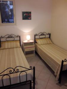ein Schlafzimmer mit 2 Betten und einem Nachttisch mit einer Lampe in der Unterkunft VILLETTA SALENTO S.M.DI LEUCA 6 POSTI LETTO in Corsano