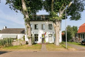 a white house with two trees in front of it at De Witte Handt in Midsland