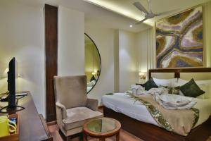 um quarto com uma cama, uma cadeira e um espelho em Hotel BR Grand With Nimo Club Amritsar -5 Mint From Golden Temple em Amritsar
