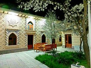 eine Terrasse mit einem Tisch und einer Bank vor einem Gebäude in der Unterkunft Colibri Traditional Guest house in Samarkand