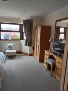 een slaapkamer met een bed, een televisie en een bureau bij Byerley House in Newmarket