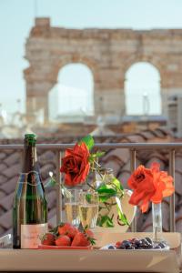 un tavolo con una bottiglia di vino e fiori di Hotel Giulietta e Romeo ***S a Verona