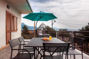a table and chairs with an umbrella on a balcony at Apartment Juric in Kastel Novi