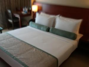 
a bed with a white comforter and pillows at Hotel Green Olive in Aurangabad

