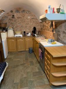 a kitchen with wooden cabinets and a stone wall at Aroma Avlis Apartment in Areopolis