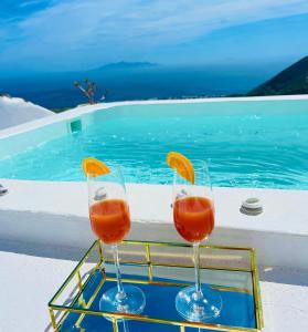 two wine glasses sitting on a tray next to a swimming pool at Amphora Villas Santorini Pyrgos in Pirgos