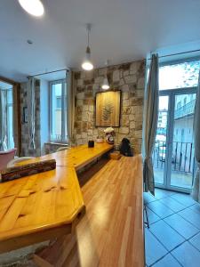 a large wooden table in a room with a stone wall at Maison LAMARTINE - Plein Centre-Ville Avec Garage & Jeux in Saint-Claude