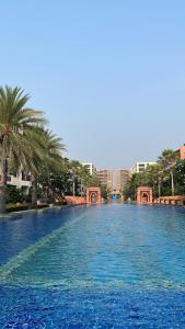 a large pool of blue water with palm trees and buildings at Baan Marakesh Hua Hin in Hua Hin