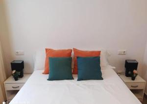 a white bed with orange and blue pillows on it at FH CAMP PRECIÓS I in Altea