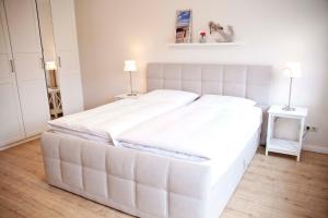 a large white bed in a bedroom with two lamps at Ferienwohnung Frieda in Scharbeutz