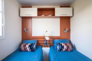 a room with two blue beds and a window at knus en modern ingericht chalet met gratis wifi in Tzummarum