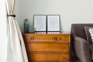 two framed pictures on a wooden dresser next to a couch at Cherry Tree Lodge in Anstey