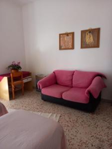 um sofá rosa numa sala de estar com uma cama em Finestra sul mare em Palizzi
