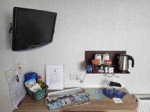 a desk with a tv on a wall with a shelf at Ashby House in Tenby