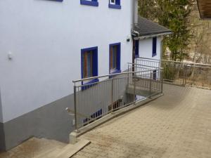 ein weißes Haus mit blauen Fenstern und einem Balkon in der Unterkunft Nolla Apartment in Thusis