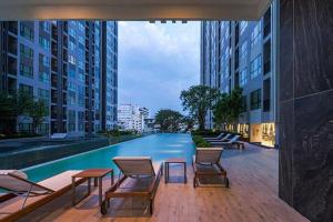 a swimming pool in a building with chairs and a table at The Base Central apartments in Pattaya Central