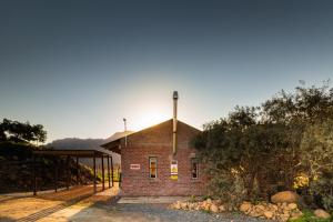 a brick building with the sun setting behind it at Bergsicht Country Farm Cottages in Tulbagh