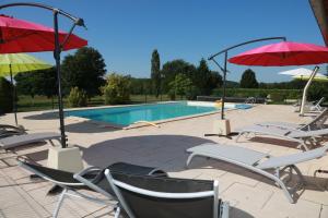 a group of chairs and umbrellas next to a pool at Papillon in Sainte-Mondane